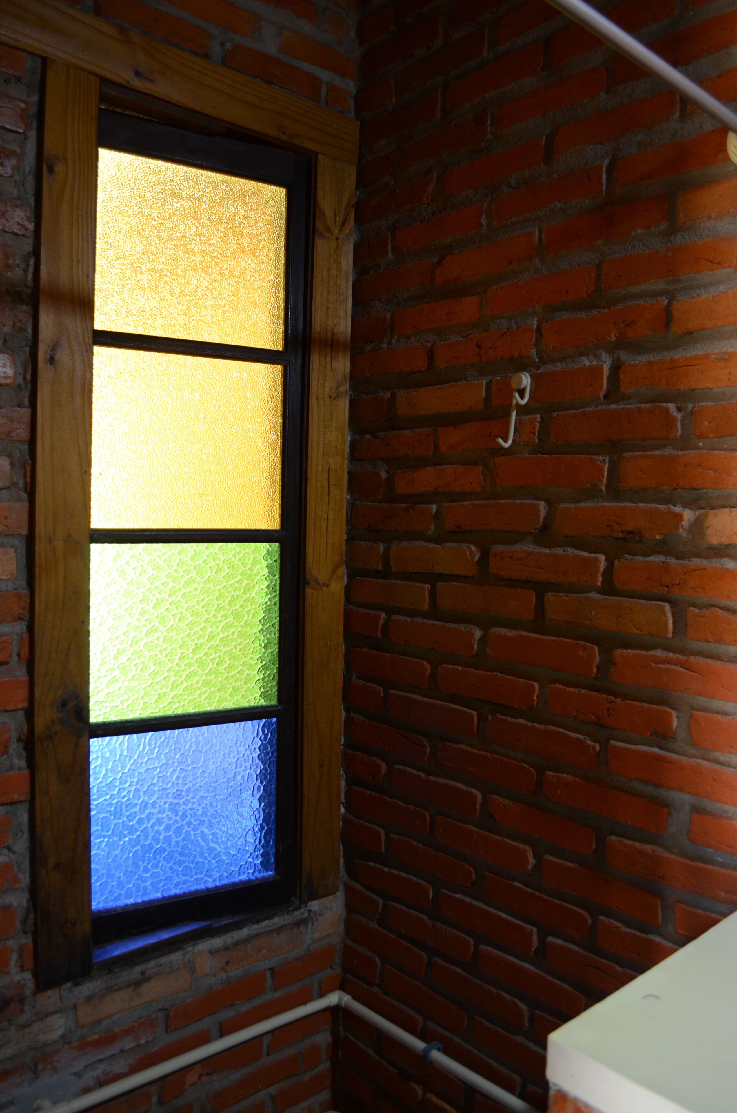 Quarto com parede de tijolos e janela com vidros foscos.
