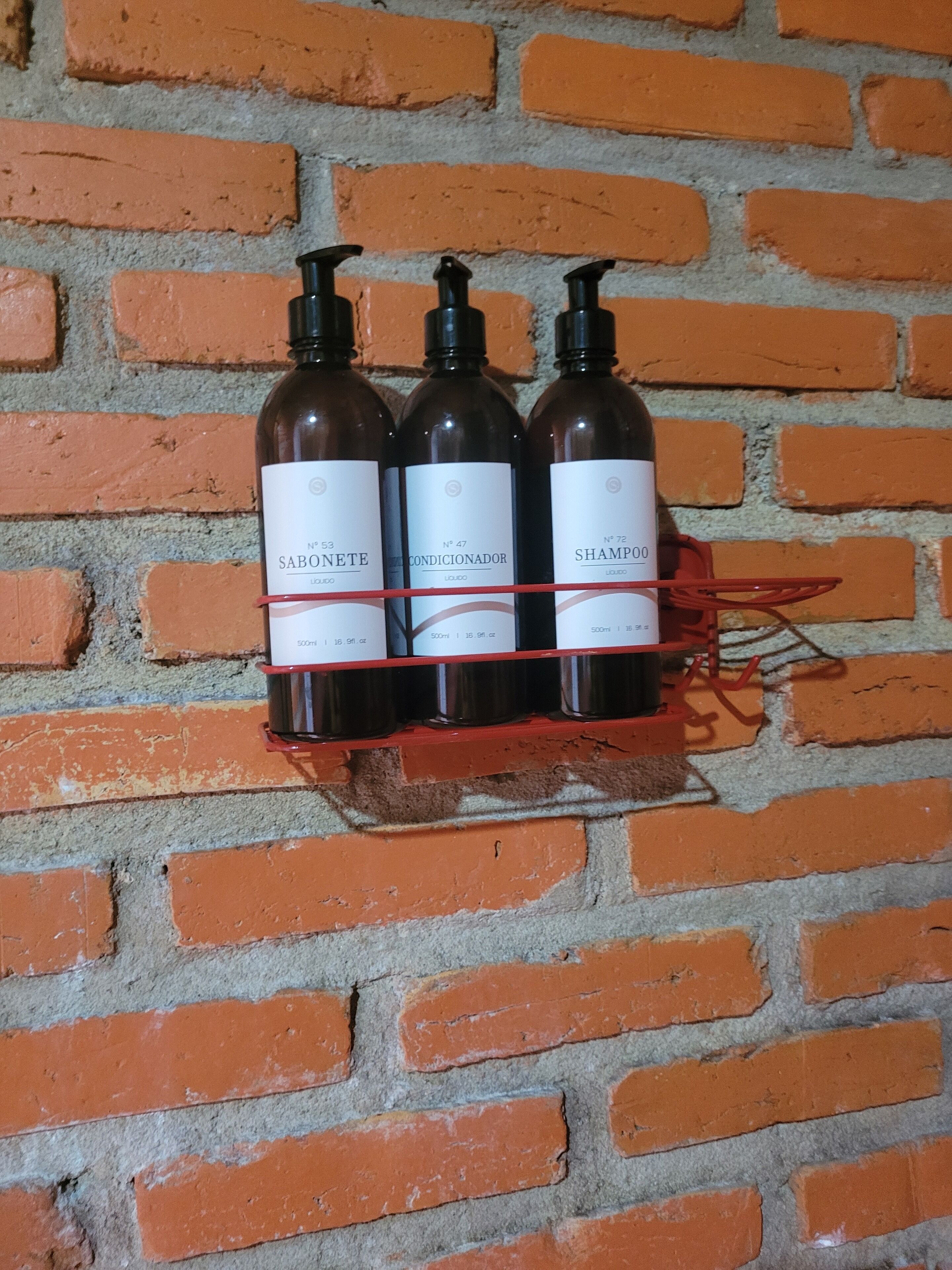 Drei Shampoo-Flaschen auf einem roten Ablagerungsvorrat neben einer Ziegelwand.