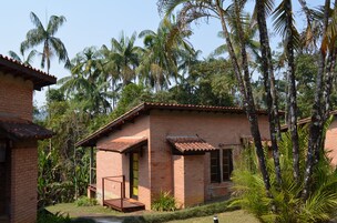 Un edificio de ladrillo con tejado de baldosas, rodeado de abundante vegetación y palmeras.