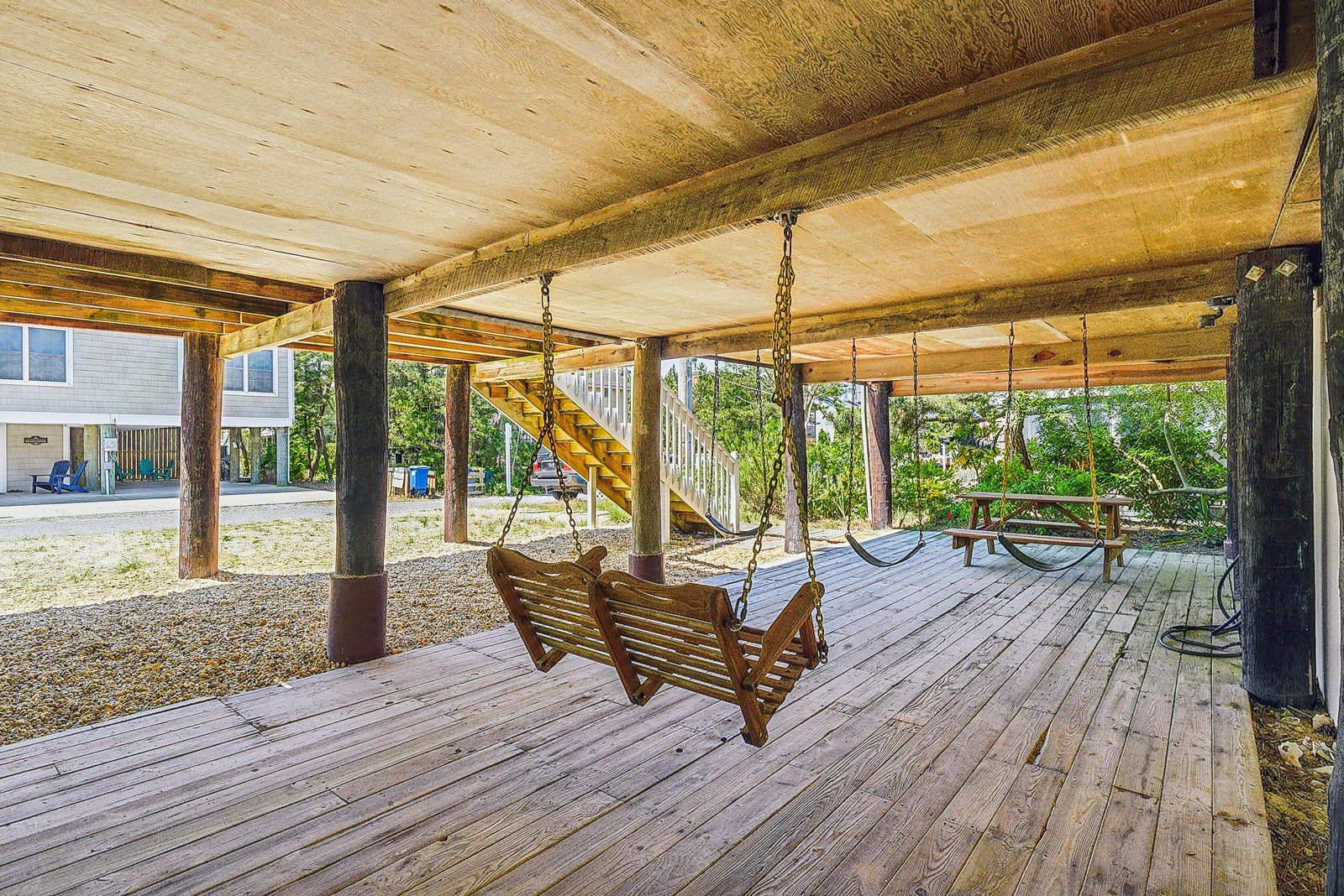 An outdoor wooden deck with a swing set and a picnic table.