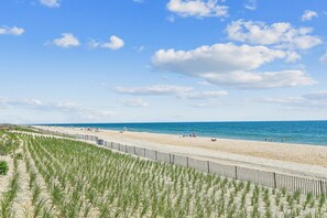 A beach with a wooden fence and vegetation in the foreground, a sandy beach, and the sea in the background. - Charming Oceanside Getaway! (South Bethany)