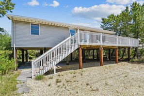 A two-story house with a covered porch and a staircase leading to the upper level. - Charming Oceanside Getaway! (South Bethany)