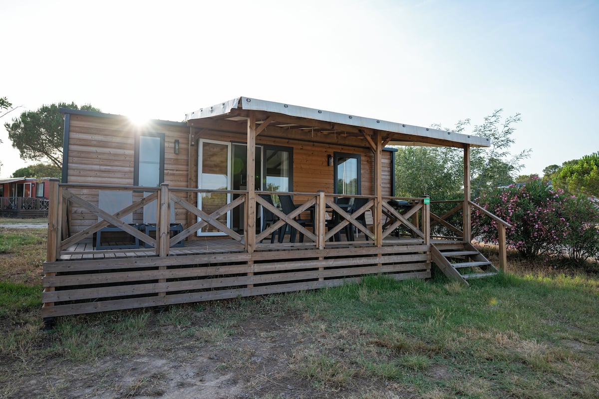 Una cabaña de madera con un porche cubierto y una escalera que conduce a la entrada.