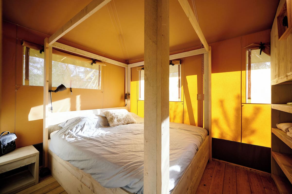 Una habitación con una cama, una mesita y una estantería con objetos.