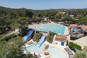 A large outdoor swimming pool with a slide, surrounded by lounge areas and umbrellas. - RCN Domaine de la Noguière (Le Muy)