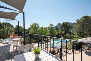 A deck with a pool, lounge chairs, and a mountain view. - RCN Domaine de la Noguière (Le Muy)