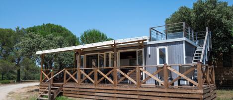 A wooden cabin with a balcony and a staircase leading to an upper level.