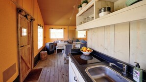 Cocina compacta con armarios de madera, un lavamanos y un comedor con una banca.