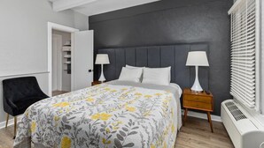 A modern bedroom with a grey headboard, a bed with a floral duvet, bedside lamps, a black chair, and a white radiator. - Blue Star #9 Location, Location 12 person hot tub! (Douglas)