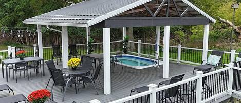 Une terrasse extérieure couverte avec une piscine, des sièges et un belvédère.