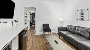 Una sala de estar moderna con un sofá gris, una mesa de centro, un televisor y una mesita auxiliar con una lámpara.