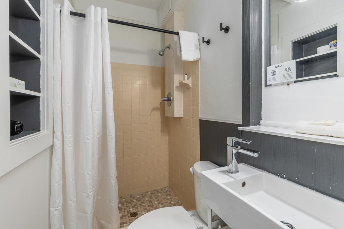 Ein Badezimmer mit Dusche, Toilette, Waschbecken und Spiegel.