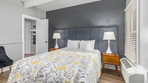 Un dormitorio moderno con una cama grande, dos mesitas de noche con lámparas, un armario y un radiador.