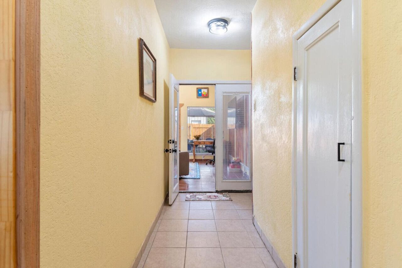 A hallway with a door on the right, a door at the end, and a picture on the wall.