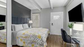 Un dormitorio moderno con cama, mesita de noche, lámpara y televisor montado en la pared.