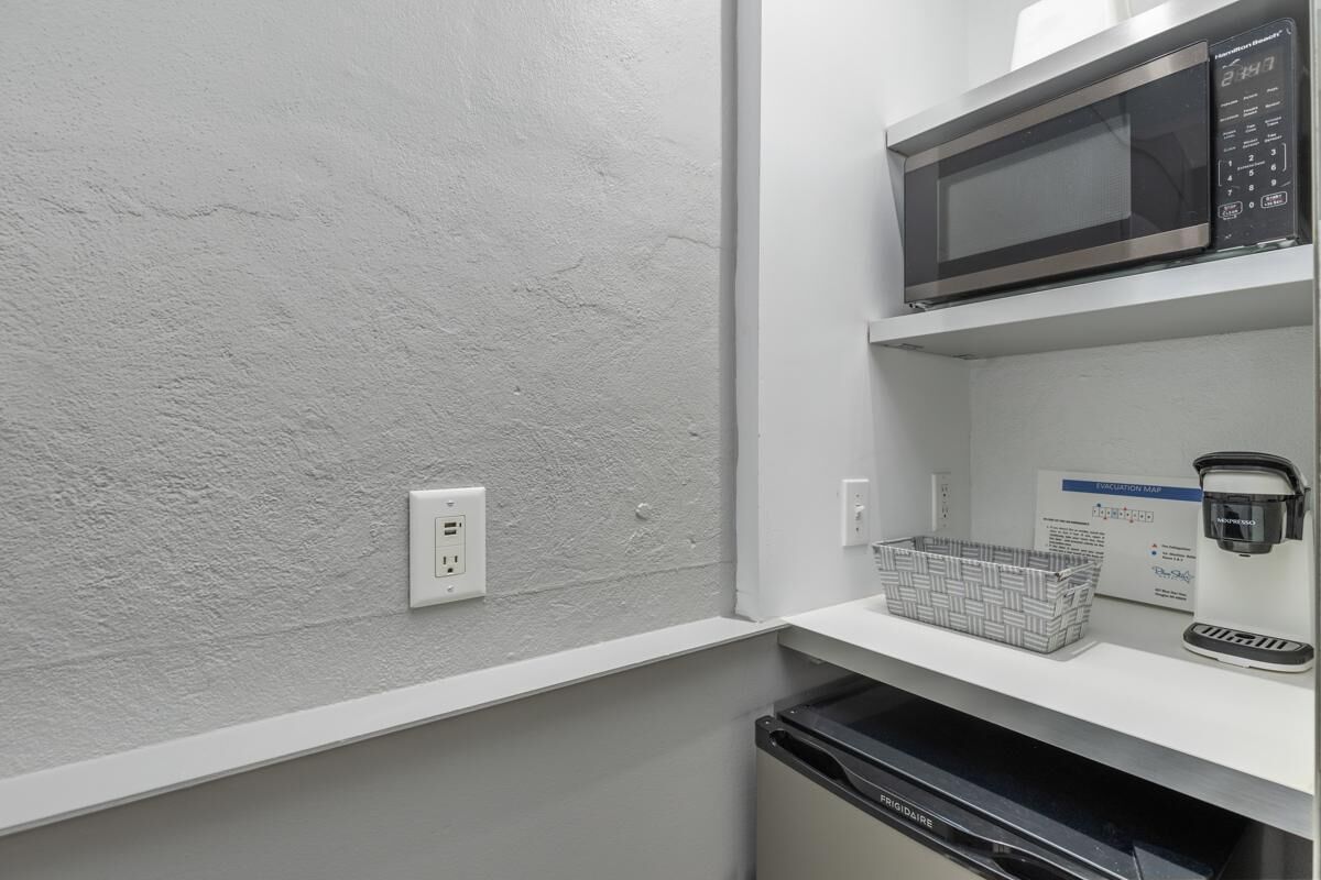 A kitchen with a microwave, a coffee machine, and a basket on the counter.