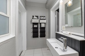 Een moderne badkamer met een wit wastafelmeubel, zwarte handdoekhouders en een grote spiegel.