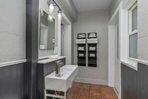 A bathroom with a white sink, a mirror with lights, and shelves with towels. - Blue Star #8 Location, Location 12 person hot tub! (Douglas)