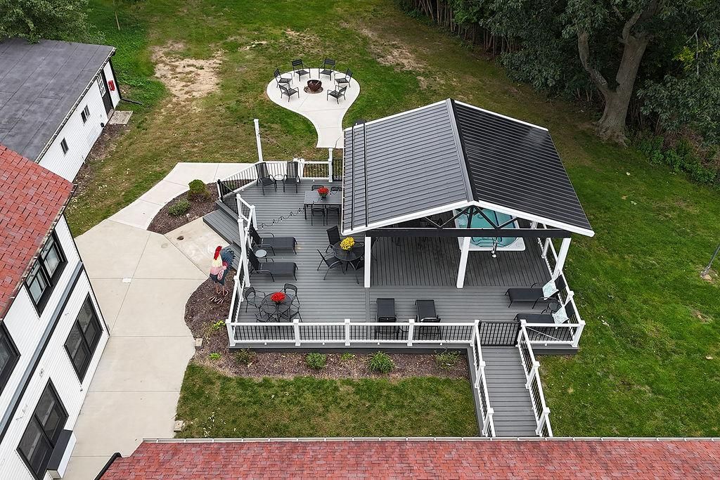 A deck with outdoor seating, a fire pit, and a covered area with a glass roof.