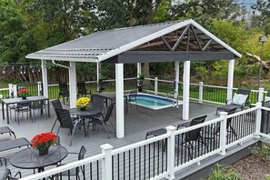 Une terrasse extérieure couverte avec une piscine, des sièges et un belvédère.