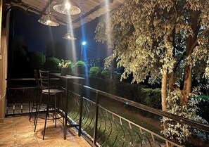 An outdoor seating area with metal chairs and a table, surrounded by a metal railing.