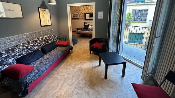 A modern living room with a sofa, a small table, and a view through a sliding door to an outdoor balcony. - Chiossetto House apartment in downtown Milan (Milano)