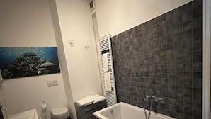 A modern bathroom with a bathtub, toilet, sink, and a shower. - Chiossetto House apartment in downtown Milan (Milano)