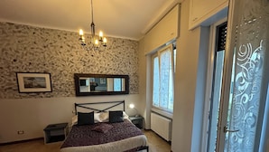A bedroom with a bed, a chandelier, a mirror, and a window with curtains. - Chiossetto House apartment in downtown Milan (Milano)