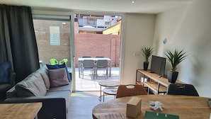 A modern office space with a sofa, a round wooden table, a TV, and a potted plant. - 2B new vacation home with terrace and air conditioning (Westkapelle)