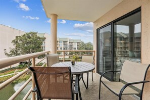 A balcony with a round table, two chairs, and a potted plant.