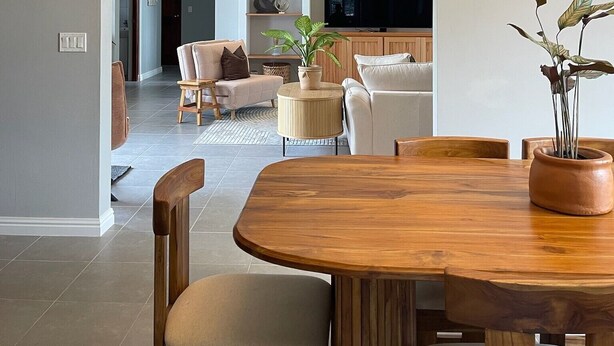 Un salon moderne avec un coin repas, comprenant une table à manger en bois, des sièges confortables et un téléviseur en arrière-plan.