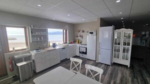 A modern kitchen with a view of the sea, white cabinets, a microwave, and a refrigerator. - Vid hafid Guesthouse (Ólafsvík)
