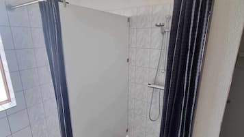 Un baño con ducha, paredes de azulejos y ventana.