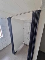 Un baño con ducha, paredes de azulejos y ventana.