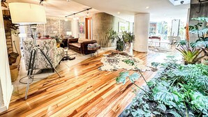 Un vaste espace de vie doté d’un plancher en bois, d’un canapé, d’une table basse et d’une grande fenêtre.