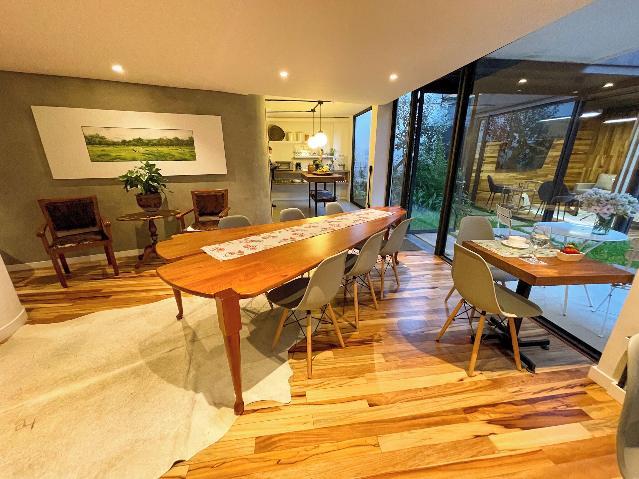 Un comedor con una mesa de madera, sillas y vistas al exterior a través de amplios ventanales.