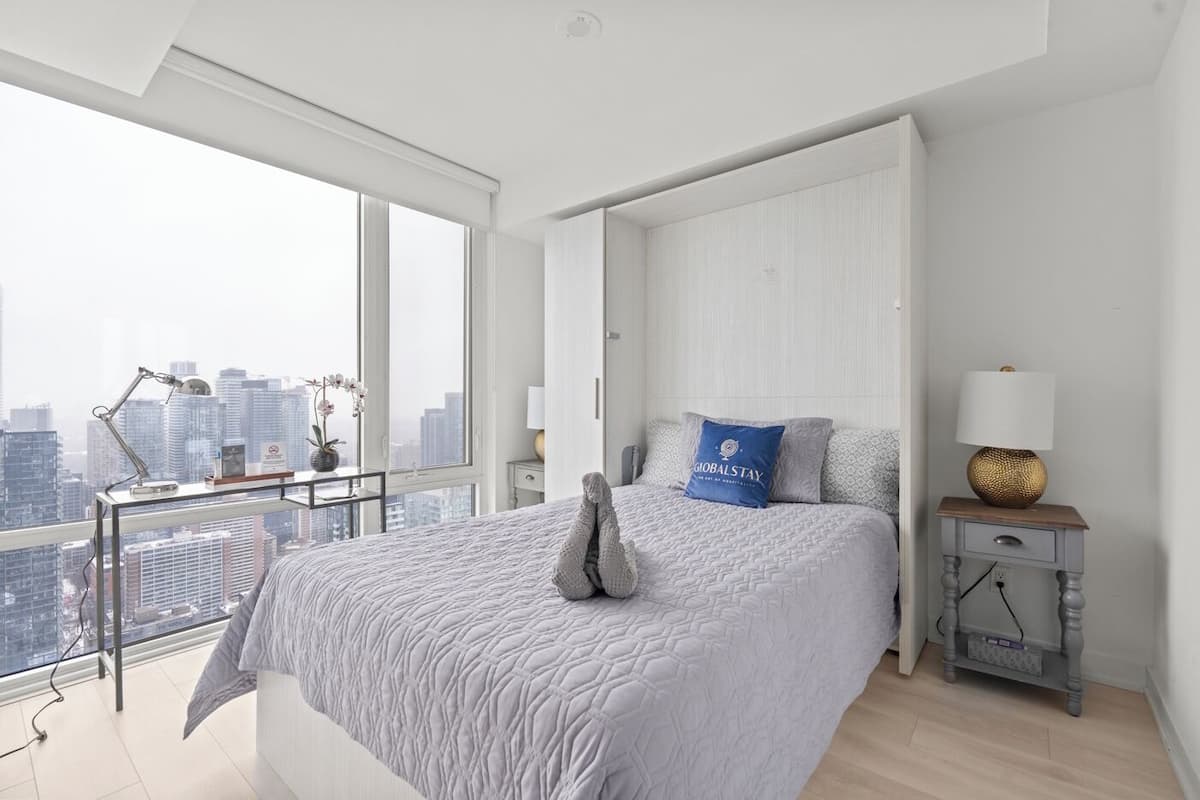 Un dormitorio moderno con una cama grande, una mesita de noche, una lámpara y vistas a la ciudad.