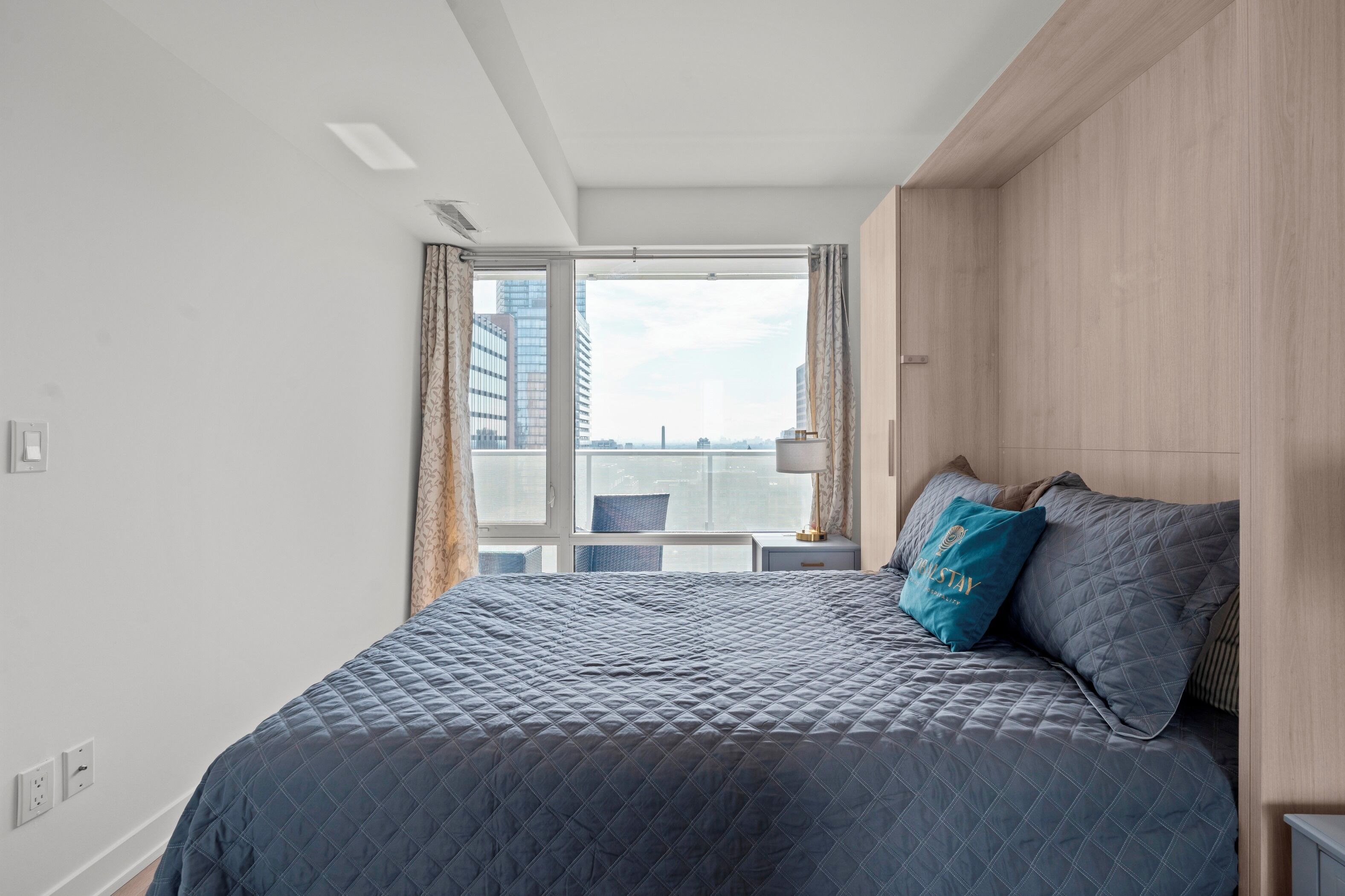 Une chambre d’hôtel avec un grand lit, une vue sur la ville et une fenêtre avec des rideaux.