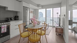 A modern kitchen with white cabinets, a stainless steel stove, and a dining area with a round table and golden chairs.