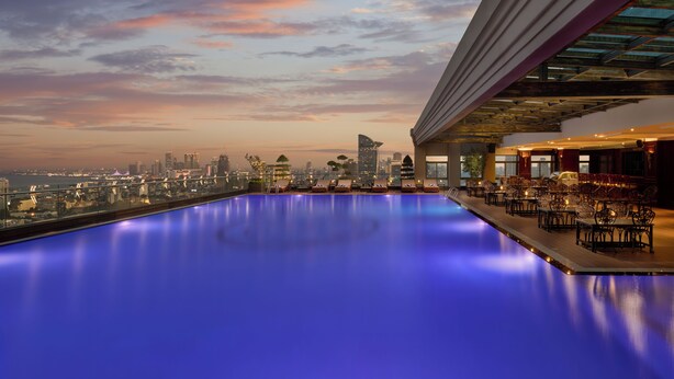 Piscina no terraço com vista para a cidade ao anoitecer.