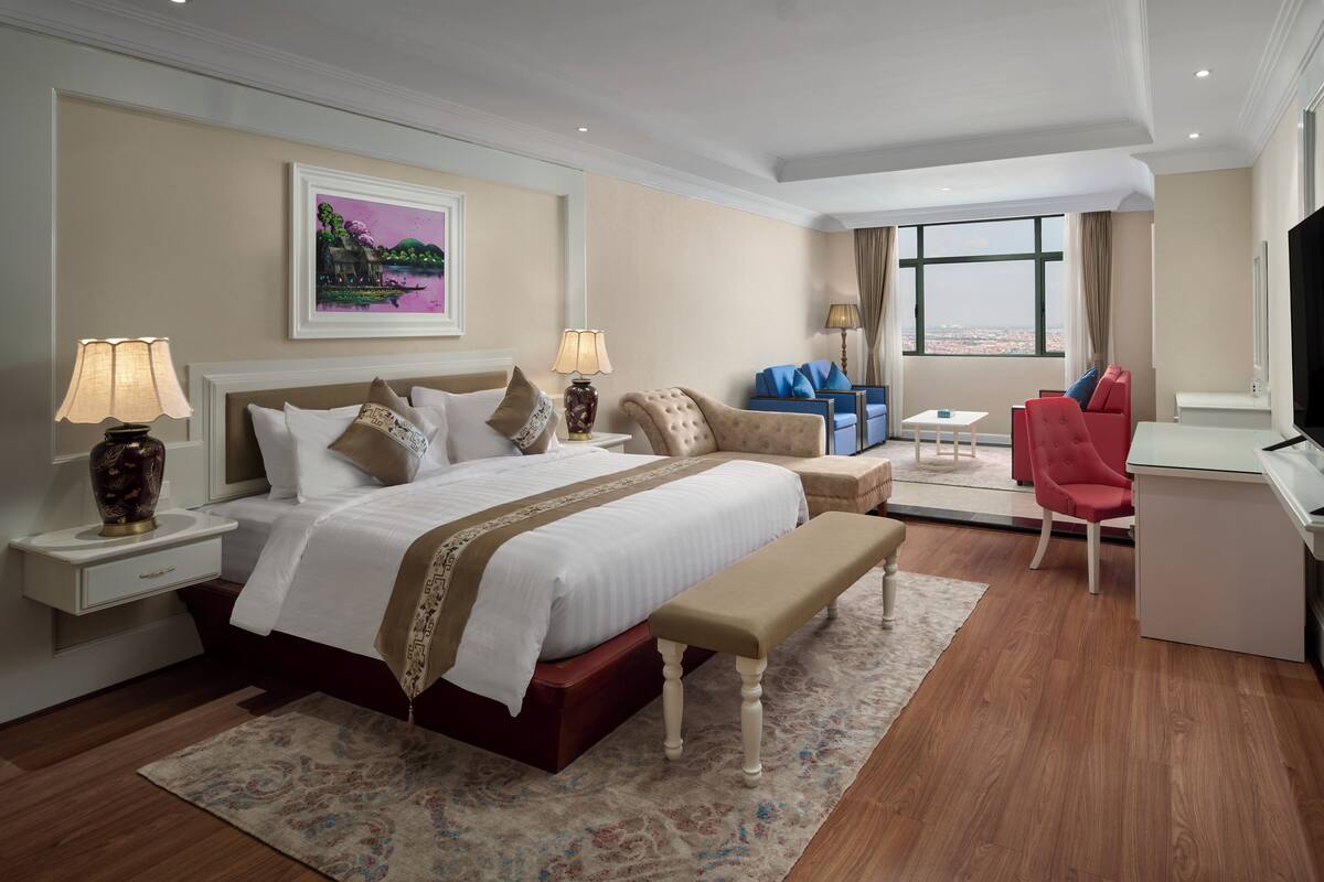 A hotel room with a large bed, a desk, a chair, and a view of the city.