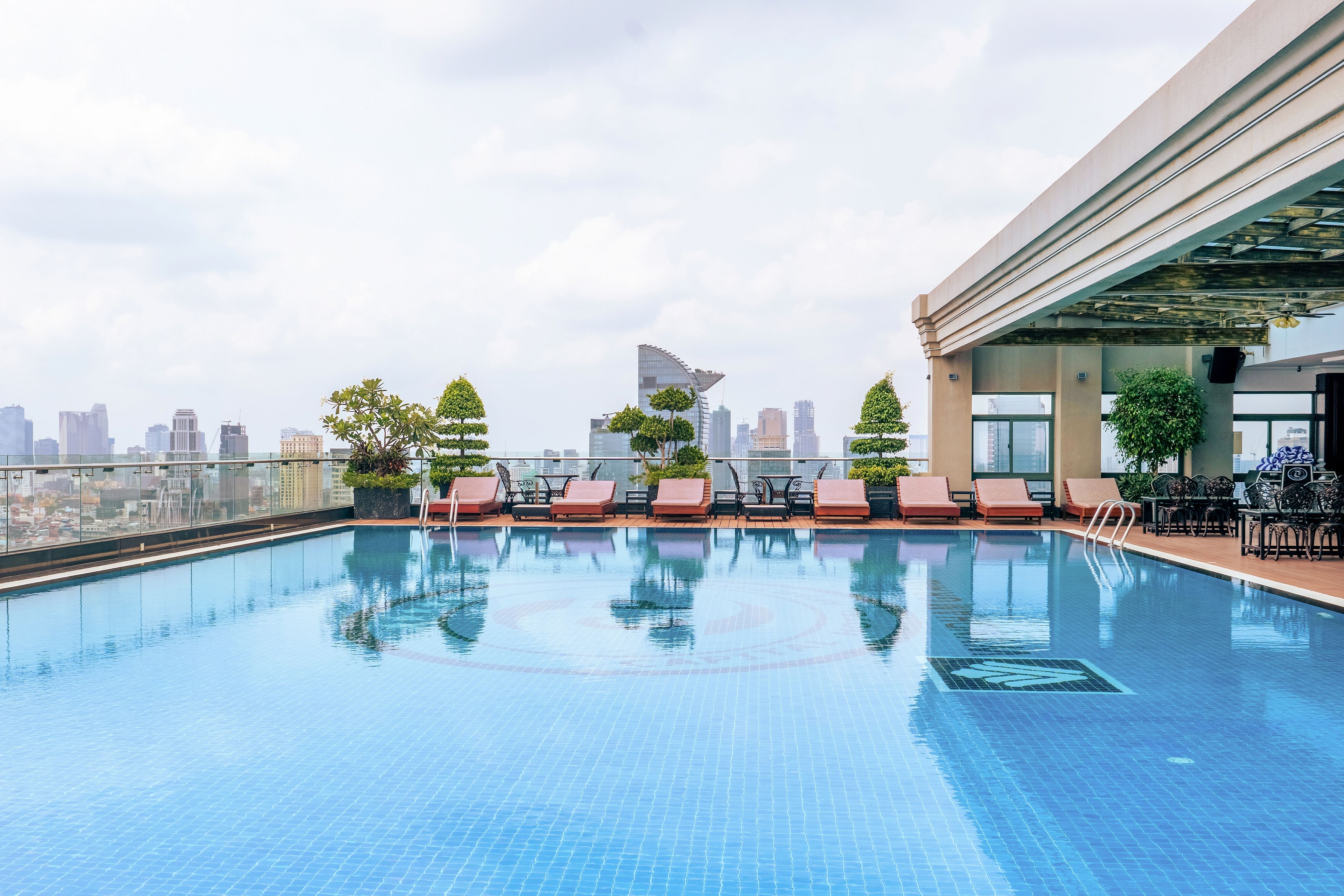 A rooftop pool with lounge chairs and a city view.
