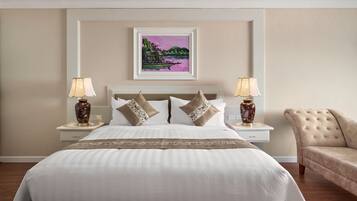 A hotel room with a large bed, two bedside tables with lamps, a chair, and a framed picture on the wall.