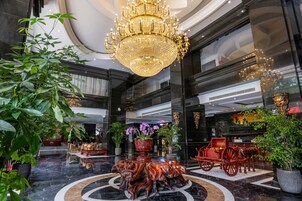Un lobby lujoso con una imponente lámpara de araña, suelo de mármol y muebles decorados.