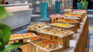 Buffet com diversos alimentos dispostos em mesas de madeira em um hotel.