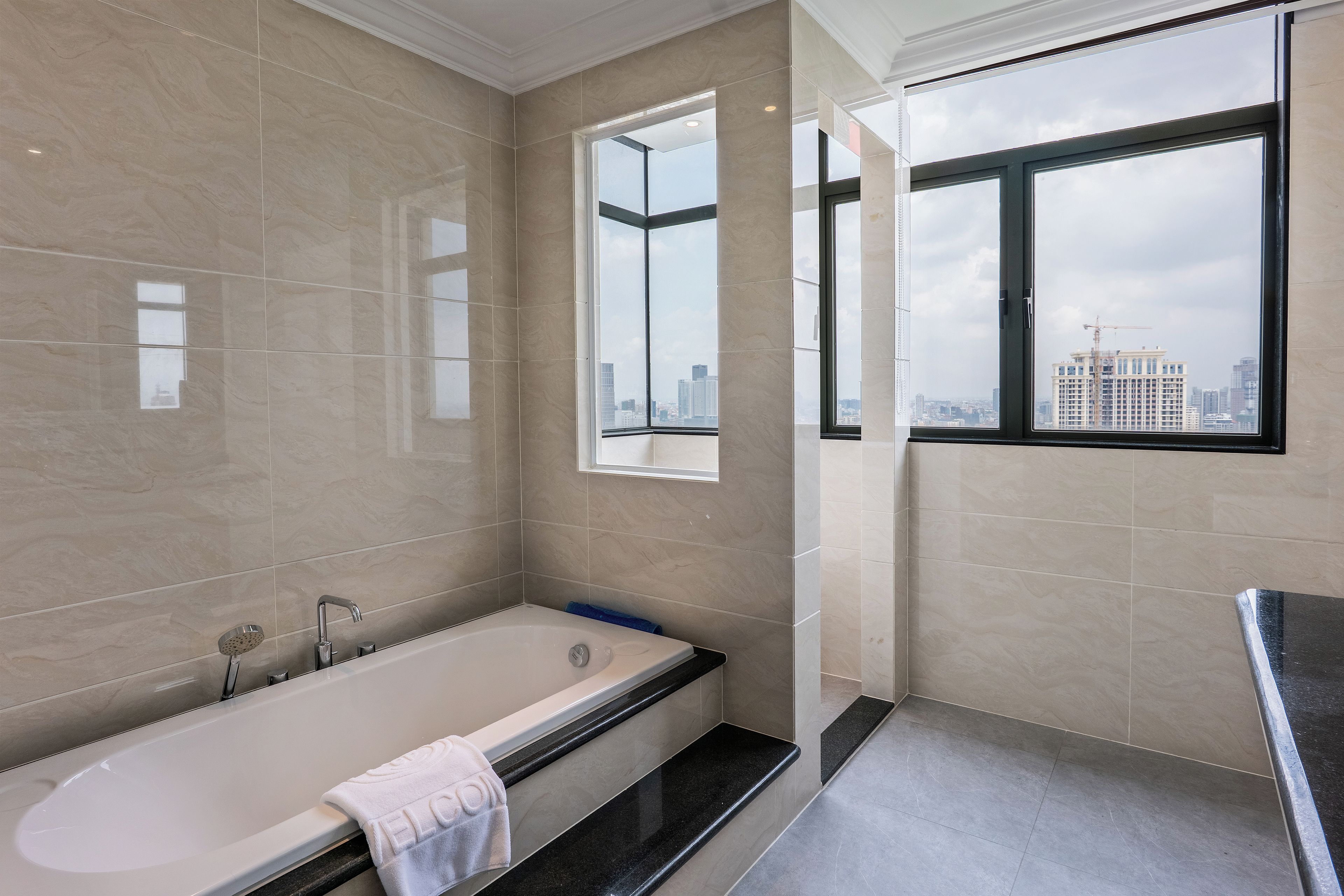 Een moderne badkamer met een badkuip, een raam met uitzicht op de stad en een grote spiegel.
