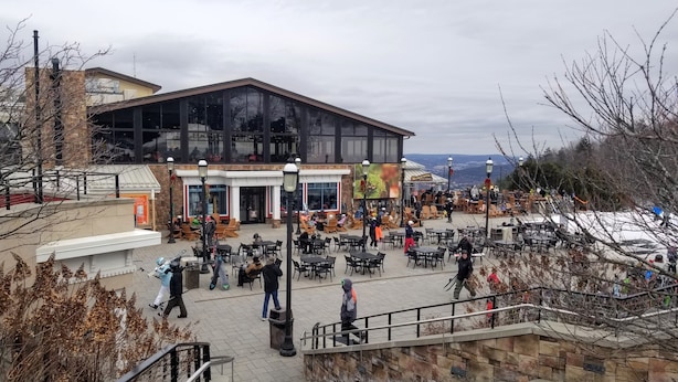 An outdoor café area with tables and chairs, a stone staircase, and a building with large windows in the background.