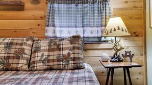 A cozy room with a plaid-patterned bed, a lamp with a tree design, and a window with a plaid curtain.