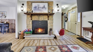 A cozy living room with a stone fireplace, a welcome sign, and a framed picture above it.