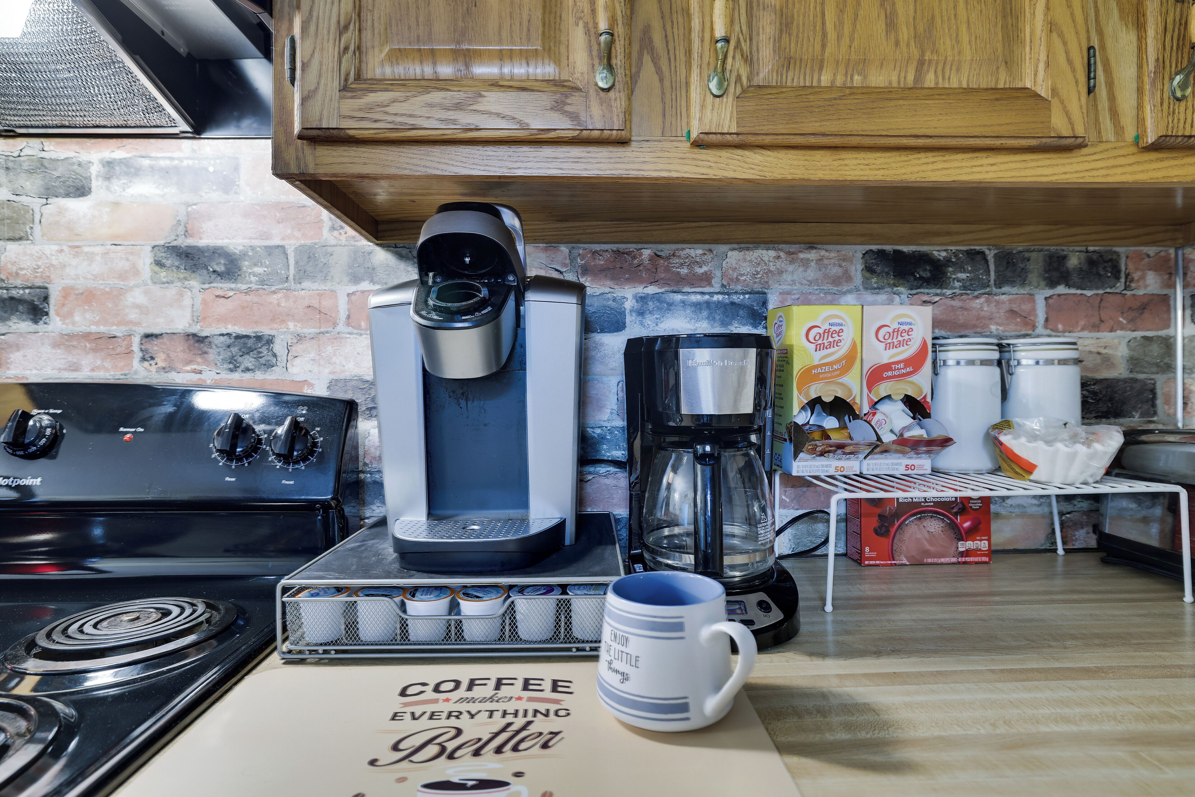 A kitchen with a coffee maker, coffee pots, and a coffee-themed placemat.